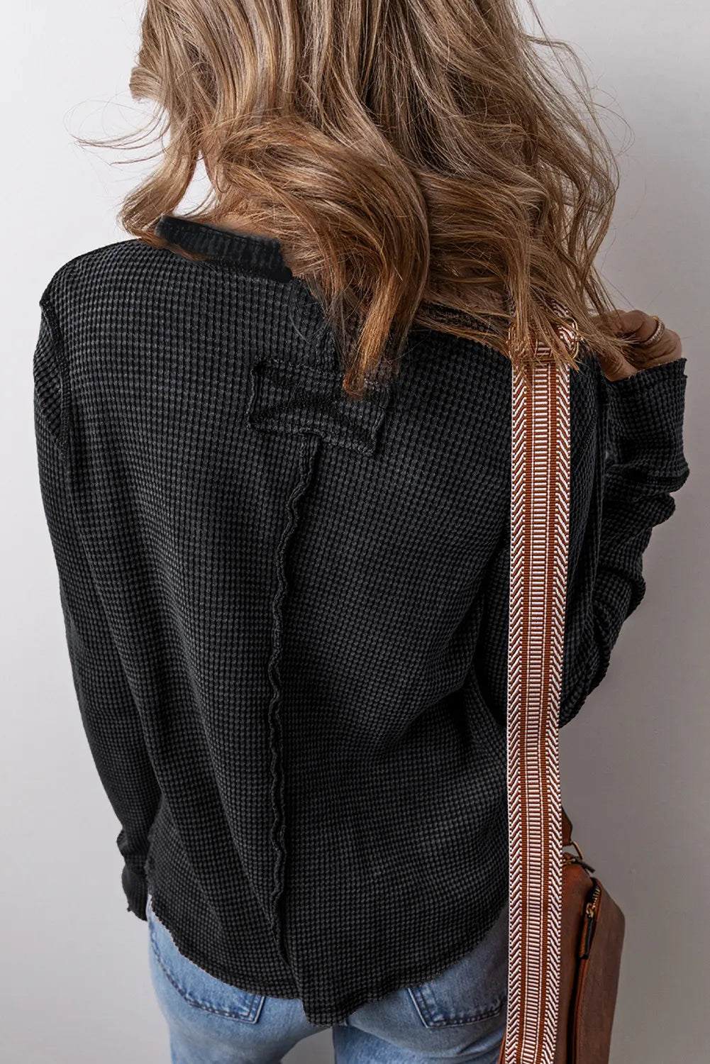 Black waffle knit blouse with seam detail and notch sleeve detail.
