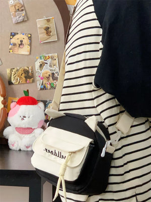 Black and white crossbody bag with cat ears and adjustable strap.