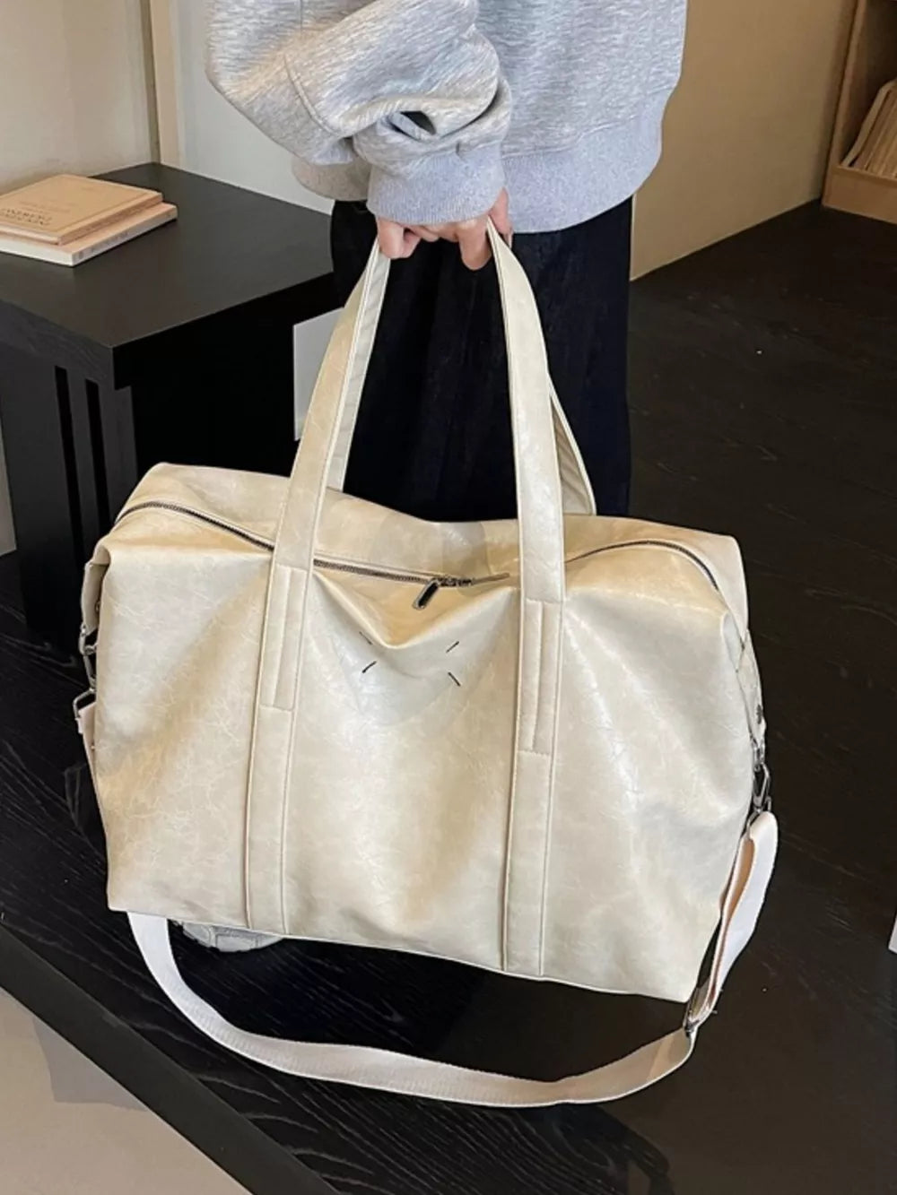 Cream white distressed vintage leather travel bag with top handles and crossbody strap.