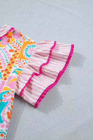 Vibrant patchwork blouse with pink striped ruffled sleeves and pom-pom trim.