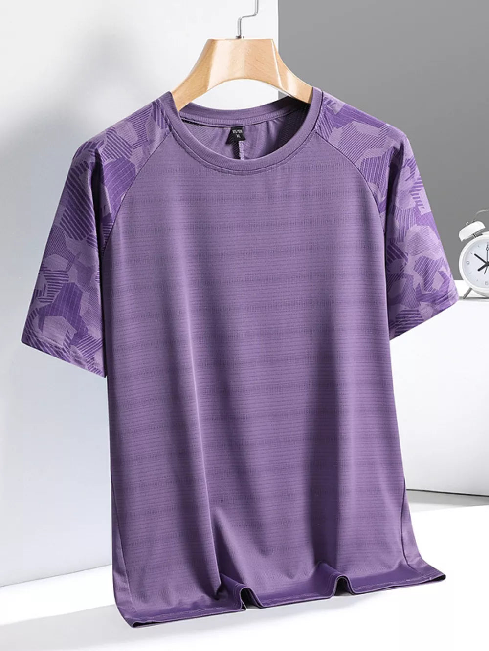 Men's purple activewear tee with patterned raglan sleeves and textured fabric.