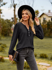 Black ruffled henley blouse with button detail and long sleeves.
