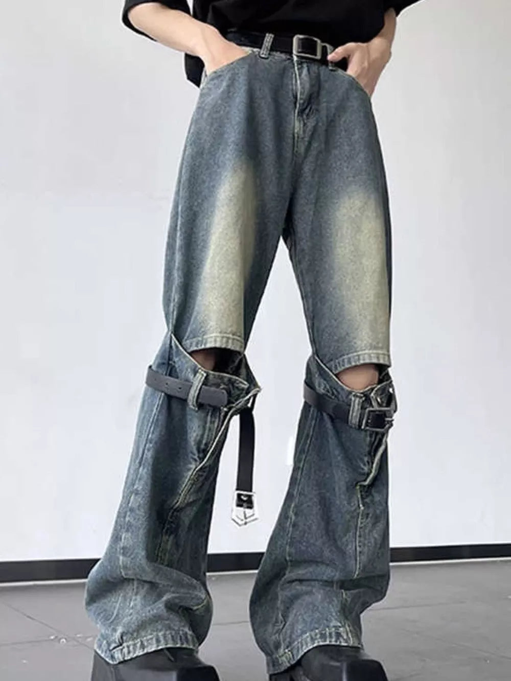 Distressed blue cotton wide-leg jeans with decorative straps and cutouts.