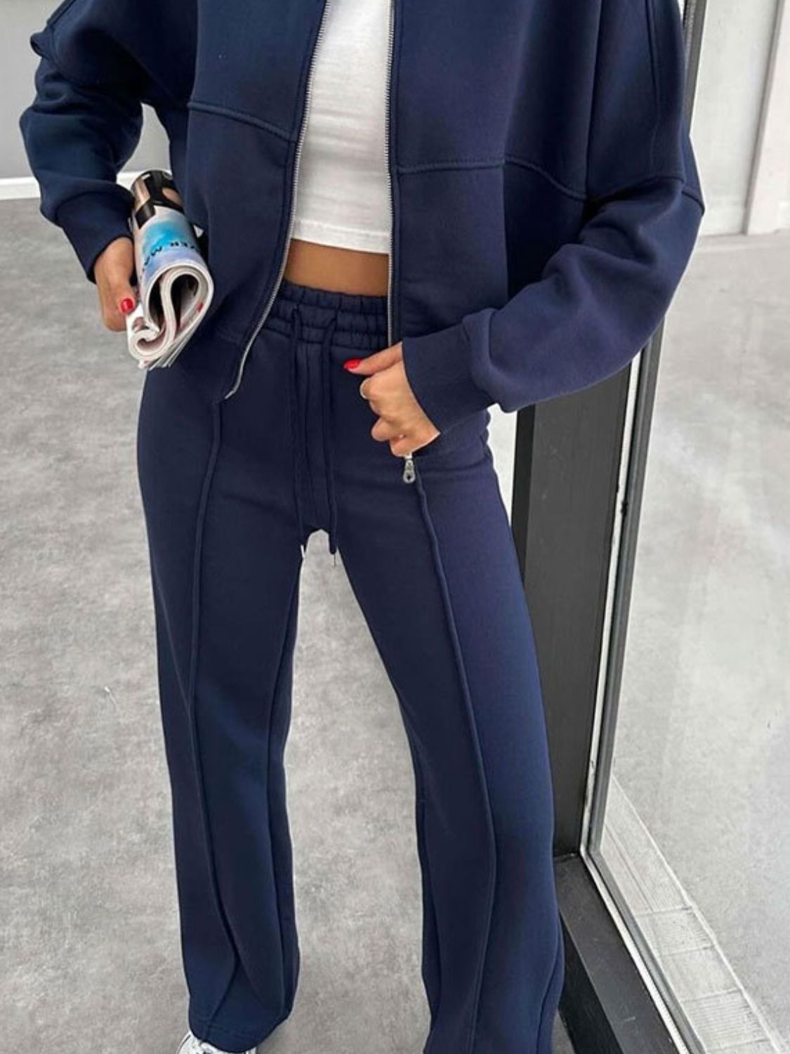 Dark blue bomber jacket and wide-leg tracksuit with drawstring waist and front zipper detail.