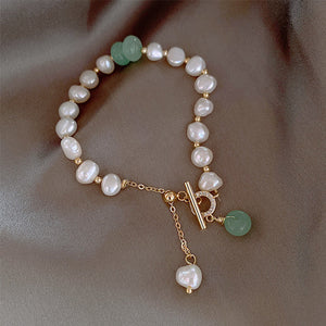 Pearl and green stone toggle bracelet with gold accents and chain detail