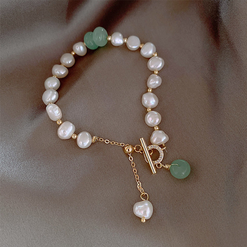 Pearl and green stone toggle bracelet with gold accents and chain detail
