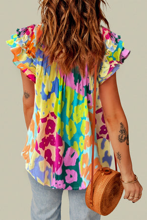 Floral patchwork blouse with ruffle sleeves in a vibrant abstract print.