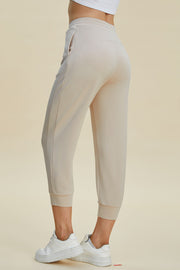 Beige joggers with drawstring waist and cuffed ankles, shown from the side.