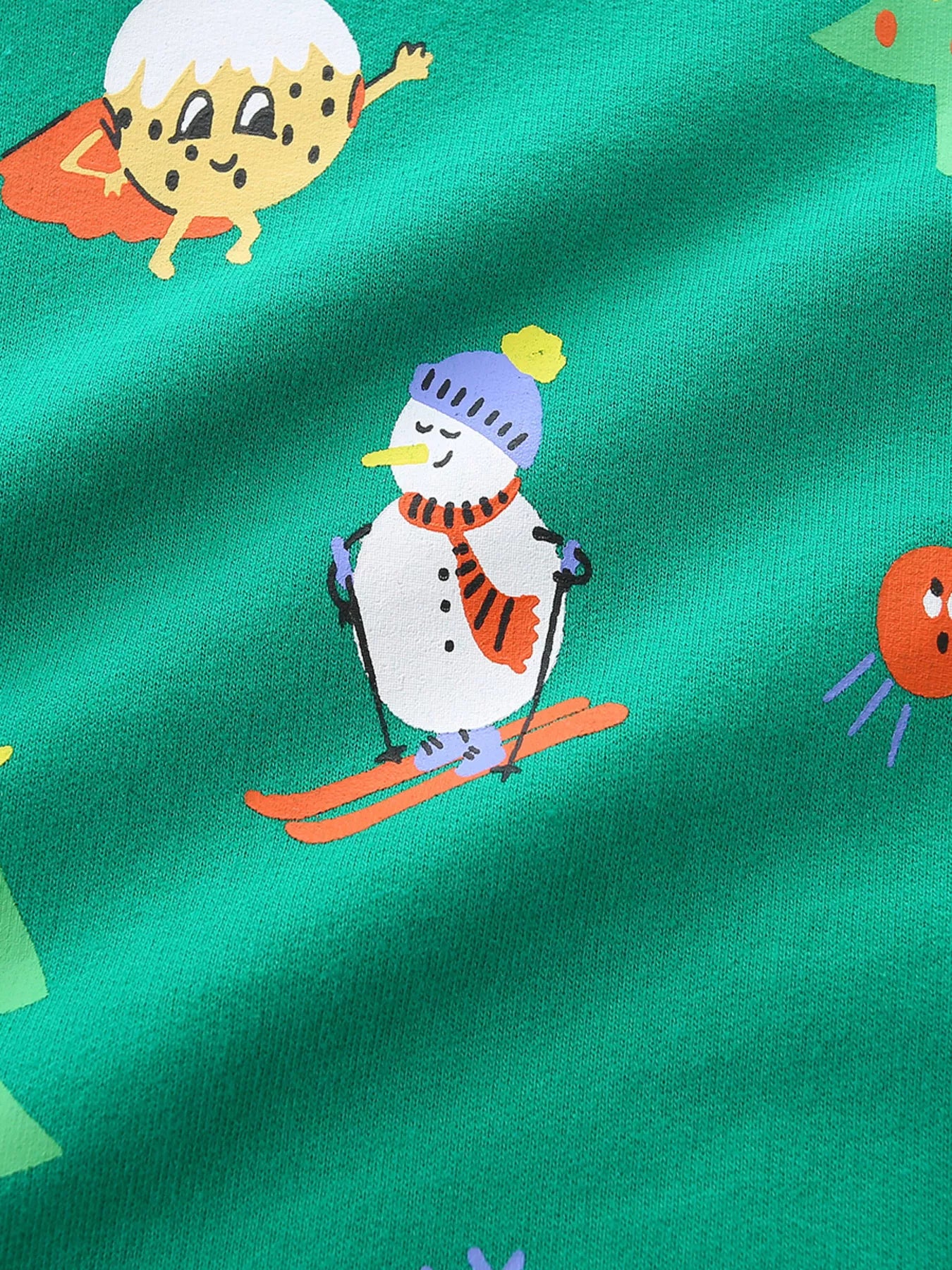Green cotton sweatshirt with festive print of a skiing snowman and a superhero cookie.