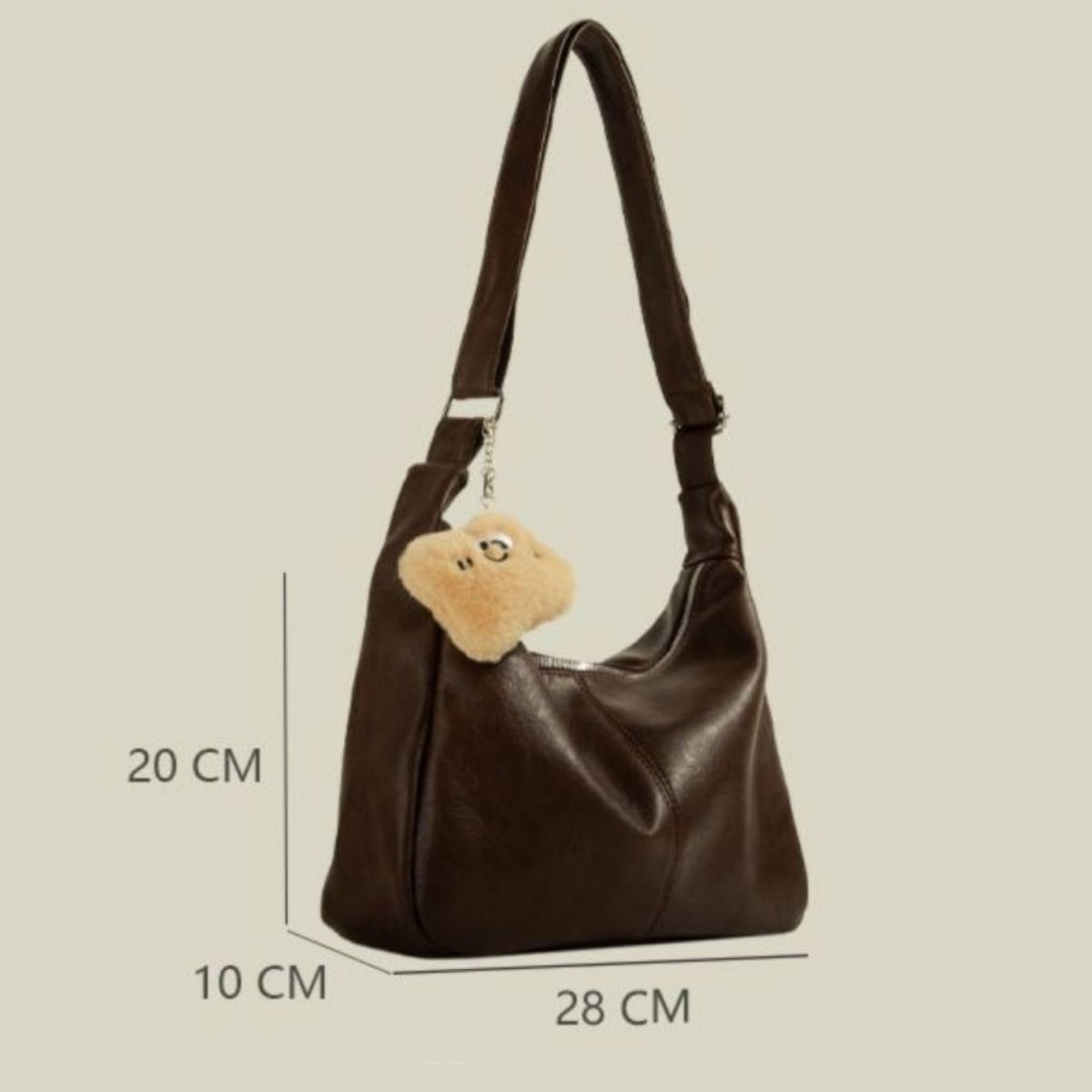 Brown pu leather crescent shoulder bag with fuzzy charm and adjustable strap.