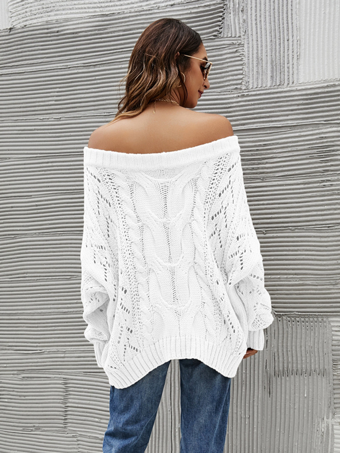 White cable knit off-shoulder sweater with slouchy fit and open knit details.