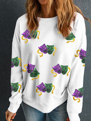 White sweatshirt with all-over sequin mask motif in purple, green, and gold.
