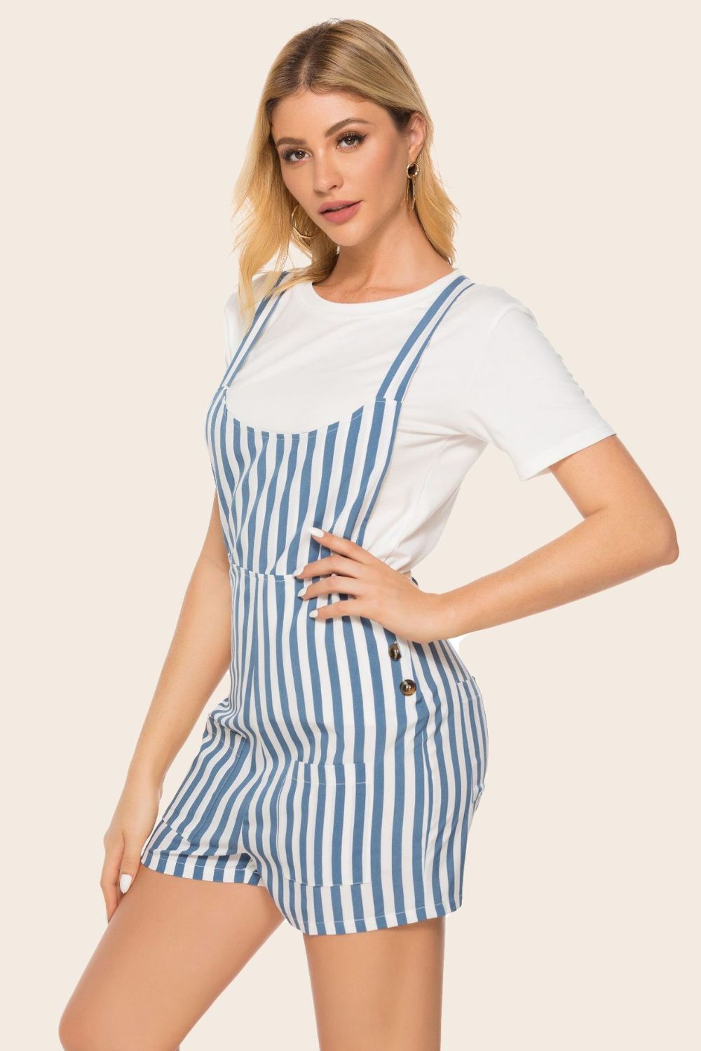 Button-detail striped pinafore romper in blue and white stripe with button accents on the side.