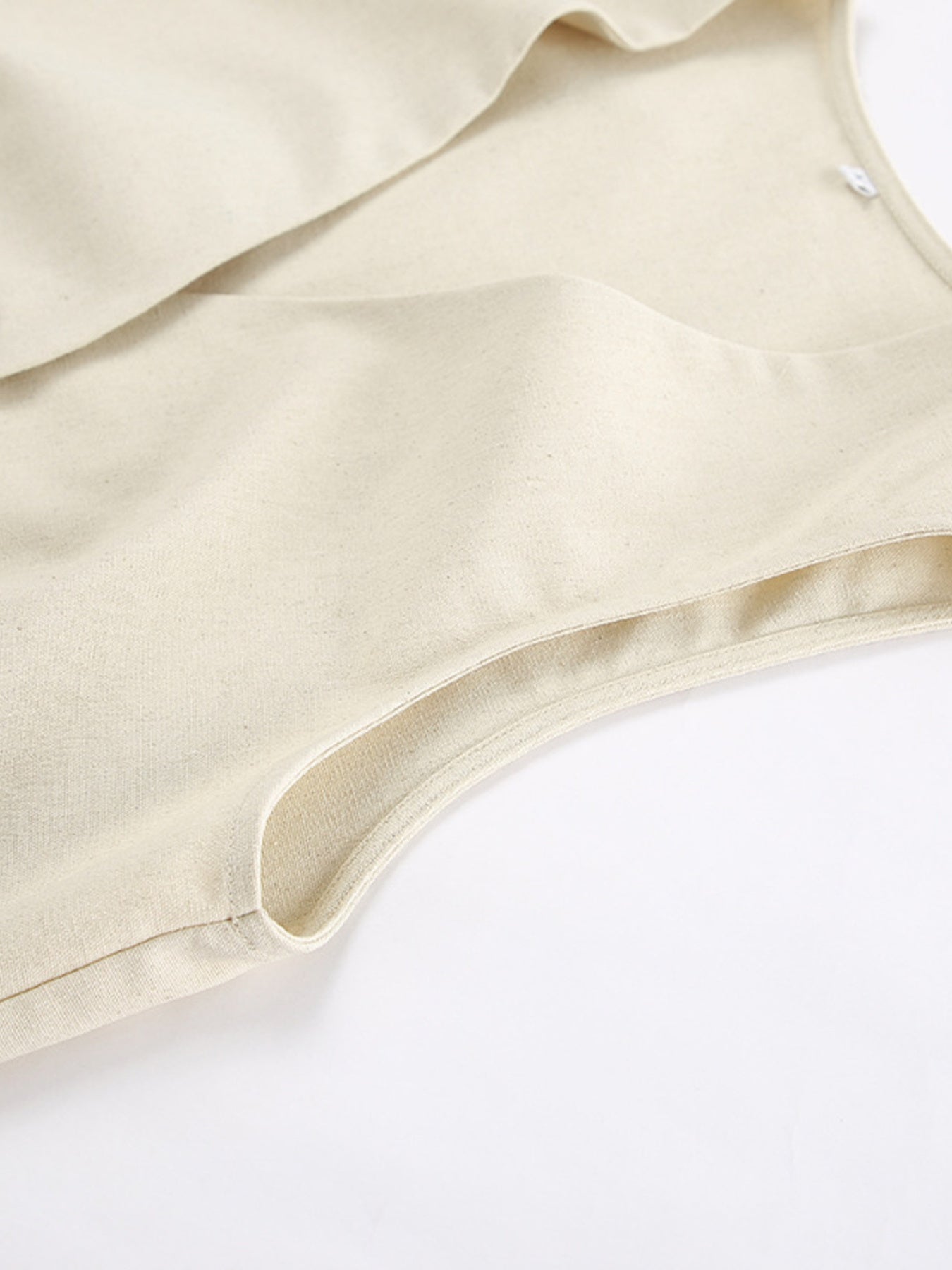 Buttoned vest and shorts set in natural cotton fabric, showing a close-up of the armhole detail.