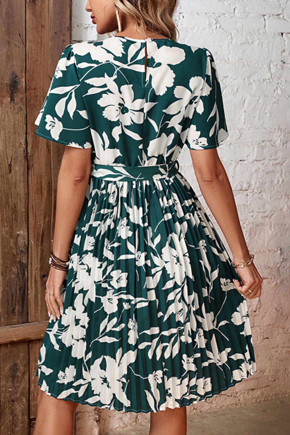Forest green floral midi dress with flutter sleeves, belt, and pleated skirt.