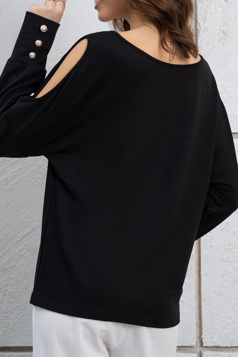 Black long sleeve top with shoulder cutouts and button cuff details