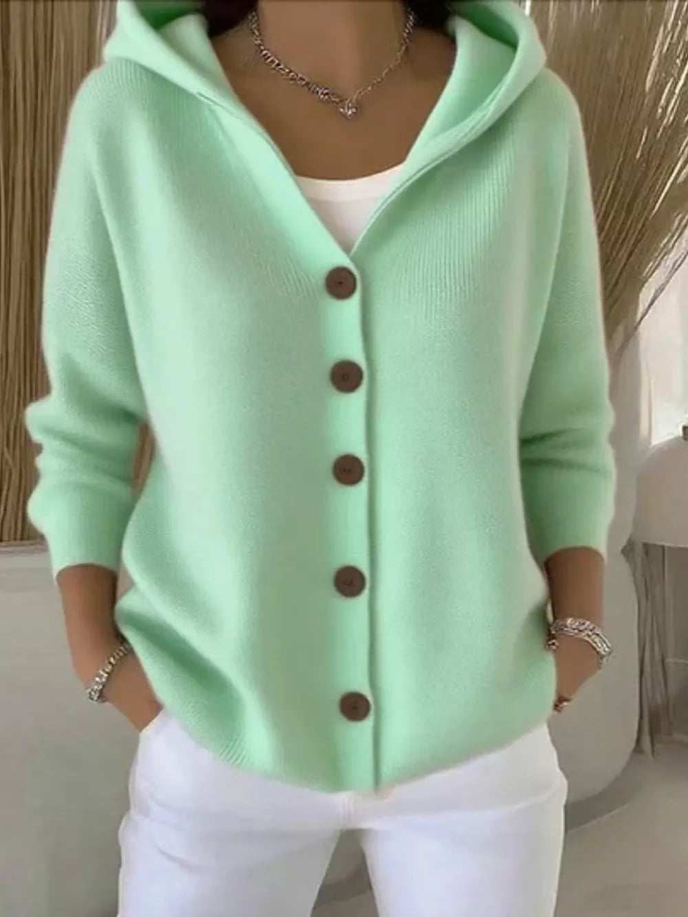 Light green knit hooded cardigan with button front and brown buttons.