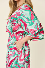Green swirl print kimono sleeve jumpsuit with elastic waist and pockets.