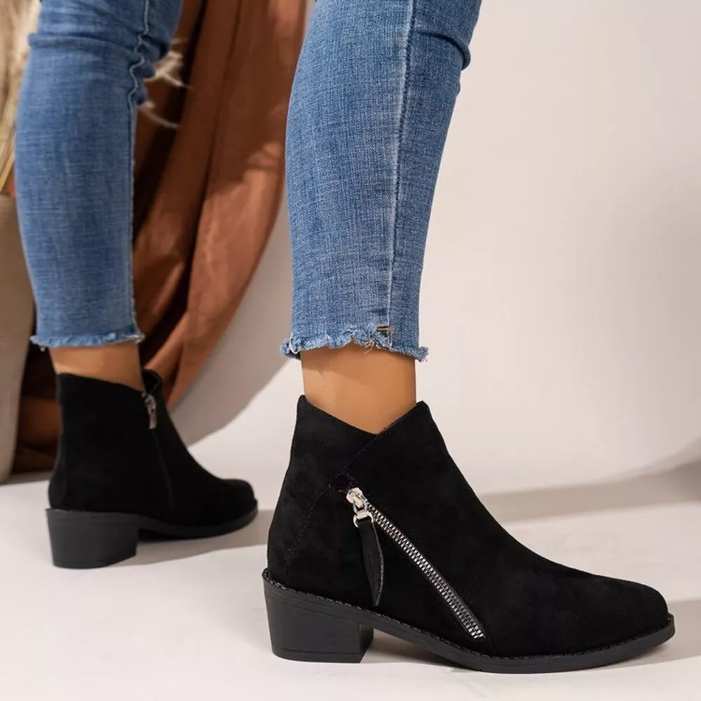 Black suede ankle boots with side zipper and block heel, styled with distressed jeans.