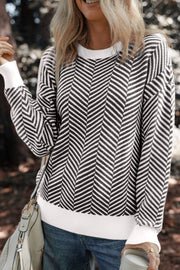 Chevron knit crewneck sweater in black with white accents, featuring a textured chevron pattern and white cuffs.