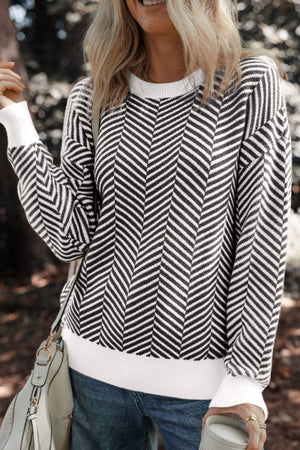 Chevron knit crewneck sweater in black with white accents, featuring a textured chevron pattern and white cuffs.