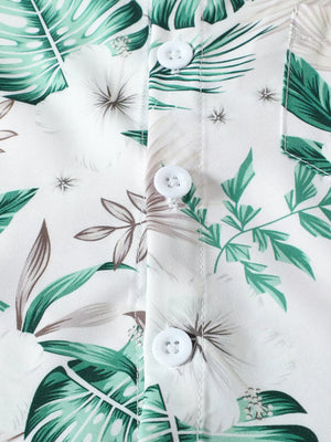 Baby shirt detail with white buttons and green tropical leaf print on cotton fabric.